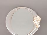 un petit miroir orné d'une fleur, posé sur une table