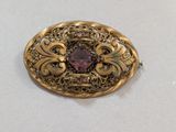 une broche ancienne en or ornée d'une pierre rose entourée de filigranes