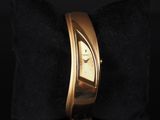 a close up of a gold wrist watch on a black pillow