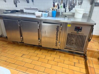 un plan de travail en acier inoxydable dans une cuisine, sur lequel sont posés tout un tas d'ustensiles