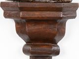 statue of a man sitting on top of a wooden shelf with a hat on his head