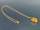un gros plan d'un collier en or avec une chaîne, posé sur une table