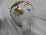 a white vase with a gold rim on a white cloth