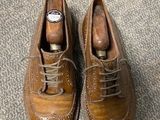 pair of brown leather shoes with laces on a carpeted floor