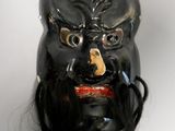 a black mask with long black hair on a white surface