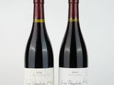 two bottles of red wine sitting next to each other on a white surface