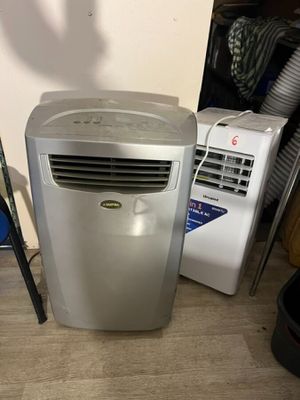 un petit climatiseur posé par terre à côté d'autres appareils électroménagers