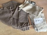 deux paires de pantalons, encore étiquetées, posées sur un parquet