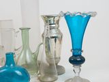 many different colored glass vases on a white surface