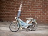 a small blue motorcycle parked in front of a brick wall