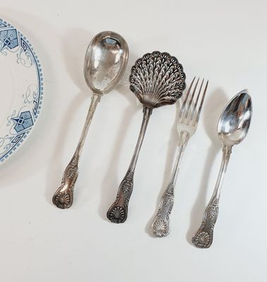 five silver spoons and two silver spoons on a white table