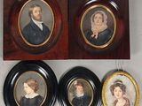 trois portraits encadrés représentant un homme et une femme, accrochés au mur
