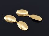two gold spoons and a spoon rest on a black surface