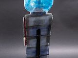 sculpture of a blue glass vase with a black base on a gray surface