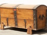 a wooden chest sitting on a sidewalk next to a white wall