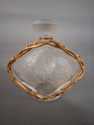 une image représentant un flacon de parfum en verre orné d'un bord doré