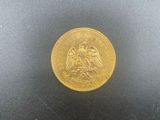 a close up of a gold coin on a black surface