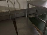 deux tables en acier inoxydable et un banc en métal dans une pièce