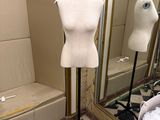 un mannequin assis sur un socle dans une pièce