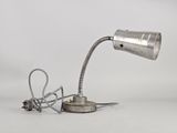 une lampe argentée, munie d'un cordon, posée sur une surface blanche