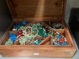 a wooden box filled with lots of jewelry on the floor