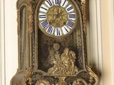 a clock hanging on the wall with a bird on top of it