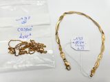 a close up of a gold necklace and some other items on a table