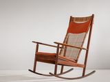 Le fauteuil à bascule est en bois et son assise est en cuir orange.