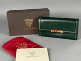 portefeuille en cuir vert avec une poignée en bambou dorée et une pochette en velours rouge