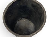 a small black bowl sitting on a white surface