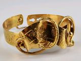 un bracelet en or sur lequel est gravée l'image d'un homme portant un casque