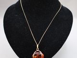 un collier avec un pendentif en verre orange sur un mannequin noir
