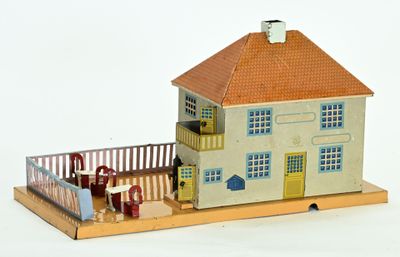 une maquette de maison devant laquelle se tiennent des personnes