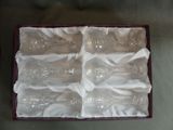 six empty wine glasses in a box on a table