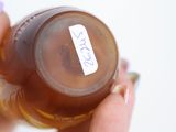 a person holding a bottle of liquid with a sticker on it