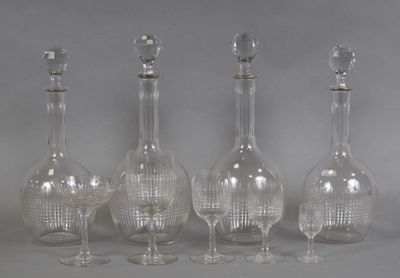 four clear glass wine glasses and a decanter on a table