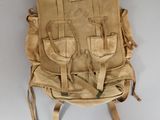 a tan backpack hanging on the wall next to a black chair