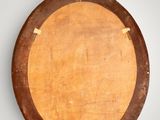 an oval mirror with a wooden frame hanging on a wall
