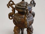 une petite urne en bronze avec un couvercle, posée sur un socle