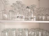 many empty glasses on a shelf in the kitchen