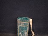 a green trash can sitting on the ground next to a black wall