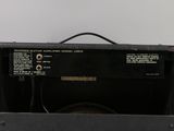 an old amplifier sitting on top of a wooden table next to a white wall