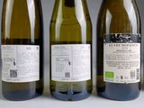 three bottles of white wine are lined up on a table