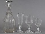 four wine glasses and a decanter sitting next to each other