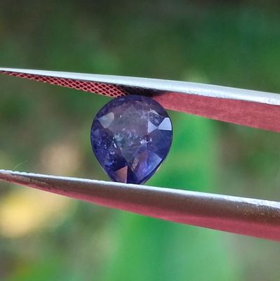 un gros plan d'un diamant bleu tenu par une pince