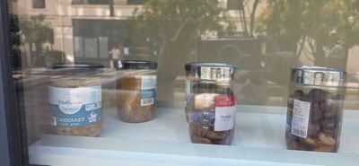 several jars of food sit on a window sill in front of a building