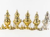 five silver and gold vases on a white surface