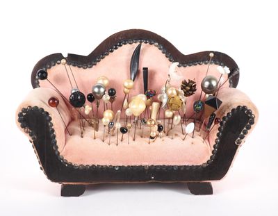a pink couch with pins on it and a bunch of pins in the back