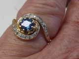 la main d'une femme tenant une bague sertie d'un saphir