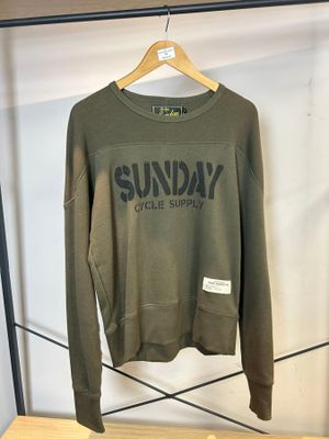 un sweat-shirt vert accroché à un portant dans un magasin de vêtements